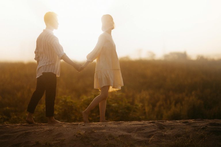 Pareja caminando de la mano al atardecer, símbolo del crecimiento personal como base de una relación duradera.