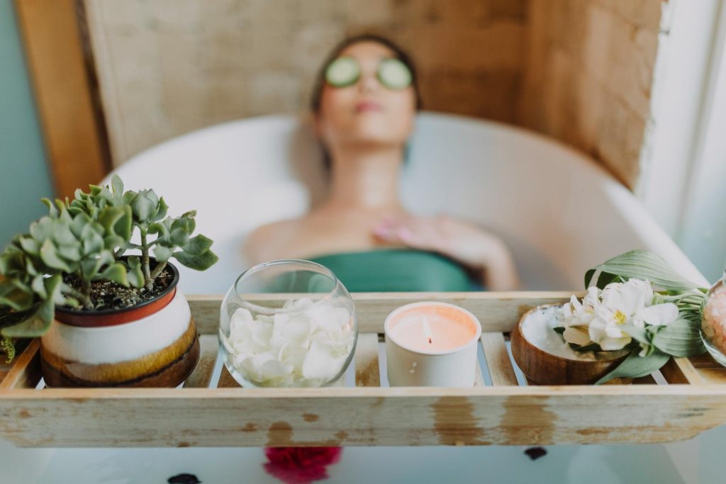 Mujer relajándose en la bañera con vela y flores, ejemplo del mito del autocuidado de Instagram frente al bienestar real y alivio de la ansiedad.
