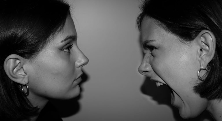Mujer expresando una emoción intensa frente a otra mujer que se mantiene sin reaccionar durante un conflicto emocional